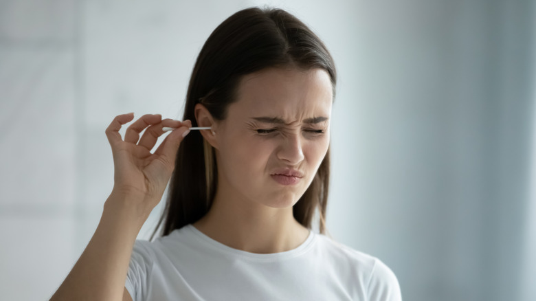 woman scowling using cotton swab