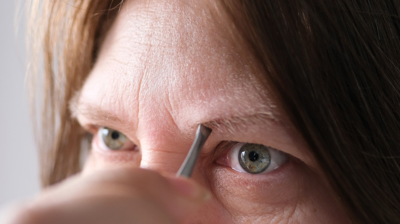 woman plucking eyebrows