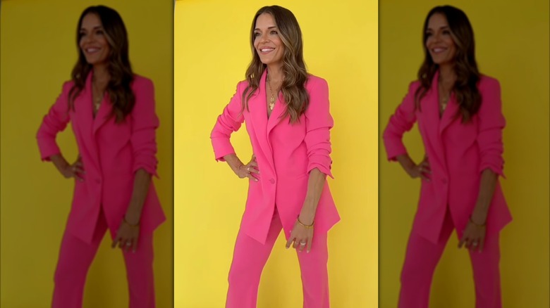 Sabrina Soto posing in a pink suit in front of a yellow backdrop.
