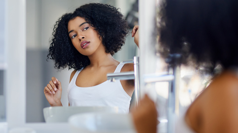 Woman studying face in mirror