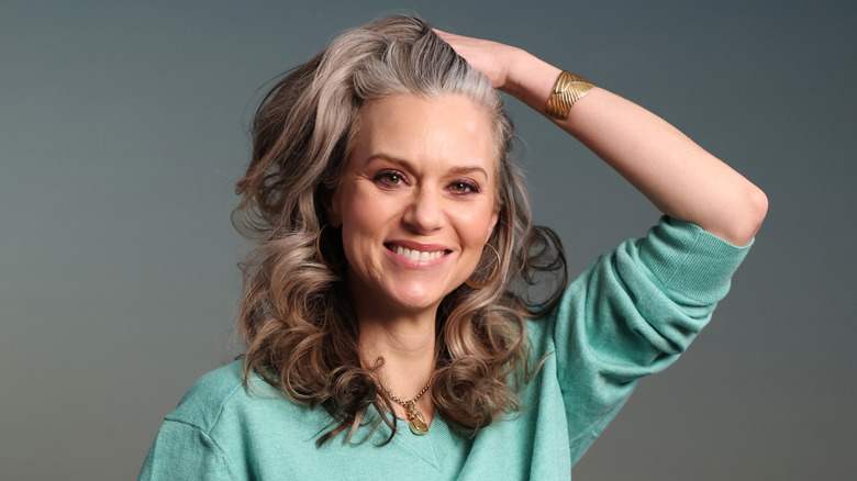 Hilarie Burton pushes her hair back and smiles during editorial photoshoot