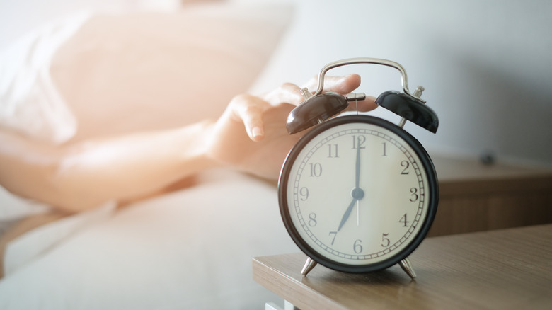 Hand reaches for alarm clock