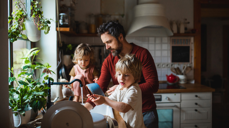 man washing dishes with children