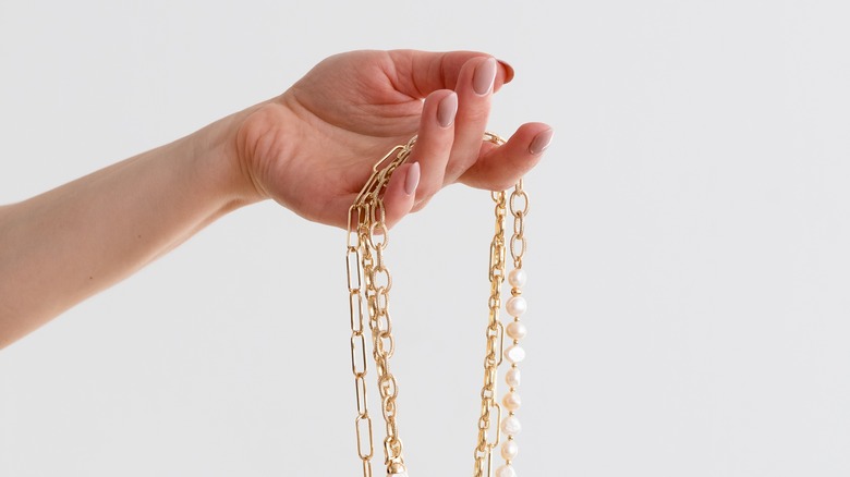 Hand holding dangling gold necklaces