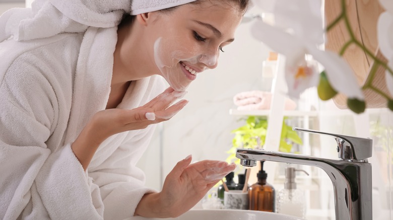 Woman washing face in sink