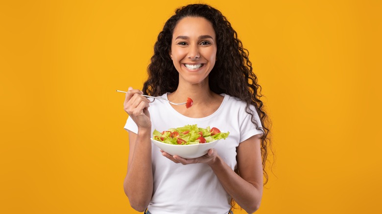 Woman eating bowl of vegetables