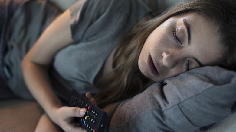Woman sleeping on couch with remote