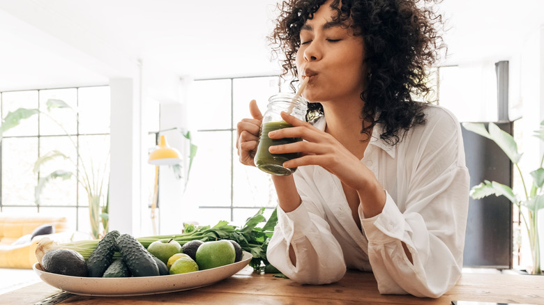 curly haired woman drinking green juice