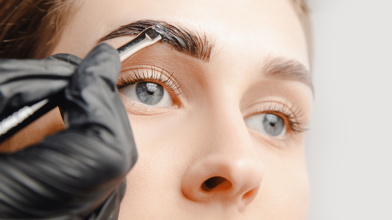 applying eyebrow tint on woman