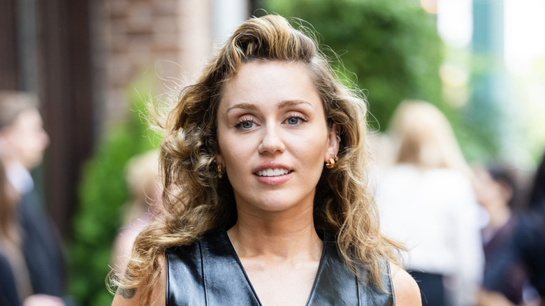 Miley Cyrus' face with a head of curls and a small smile