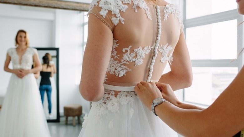 Person buttoning wedding dress back