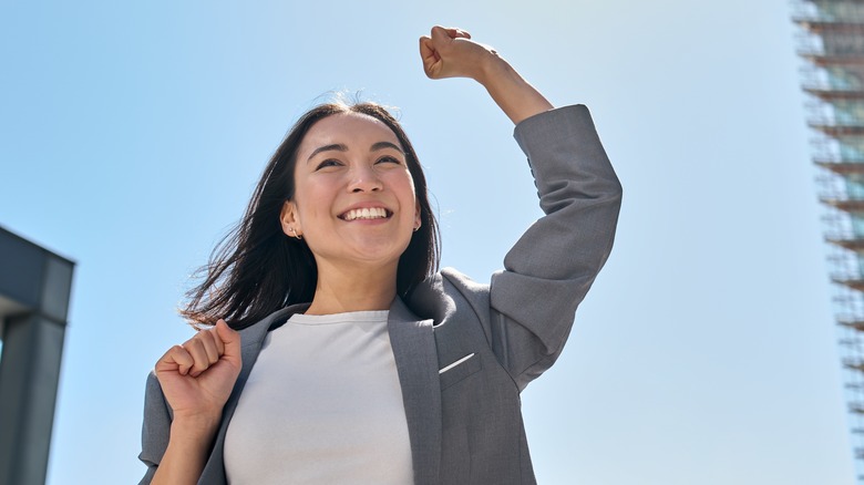 Smiling businesswoman raising hands in success