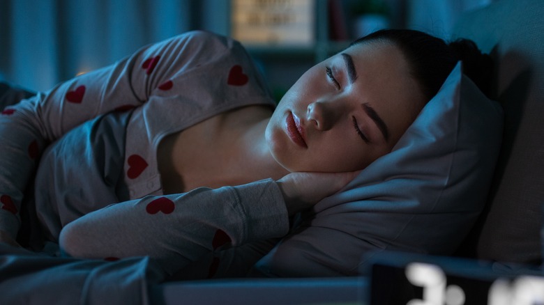 Girl sleeping next to alarm clock