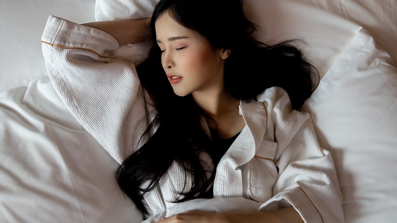 A woman sleeping on white sheets and pillows