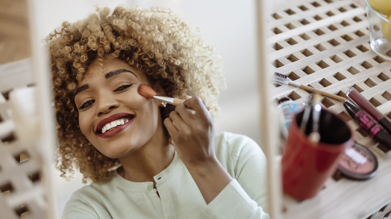 Woman smiling applying blush