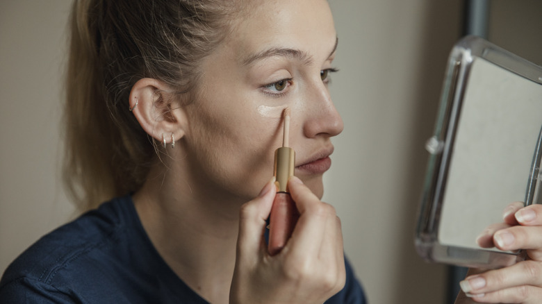 woman applying concealer under eyes