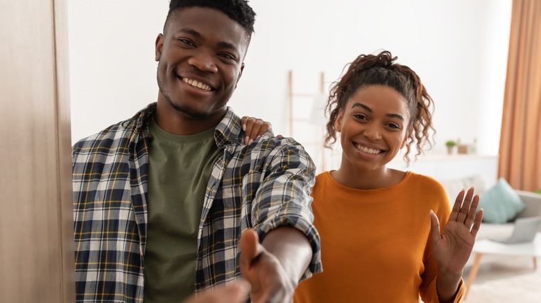 Young Black couple greeting guest