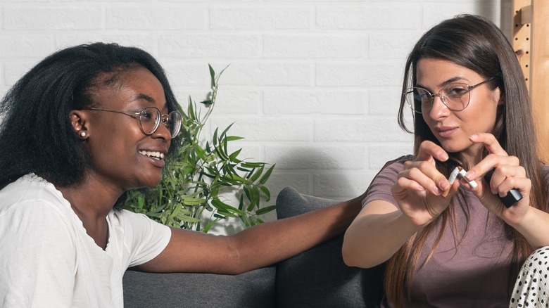 Friend smiling at woman breaking cigarette