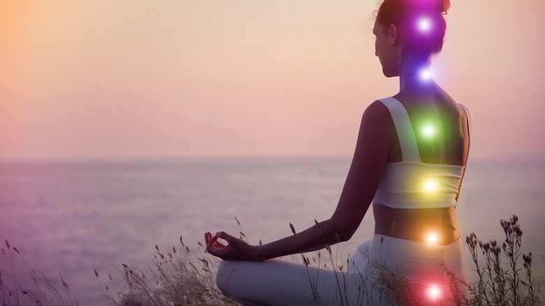 Woman meditating with chakras illuminated