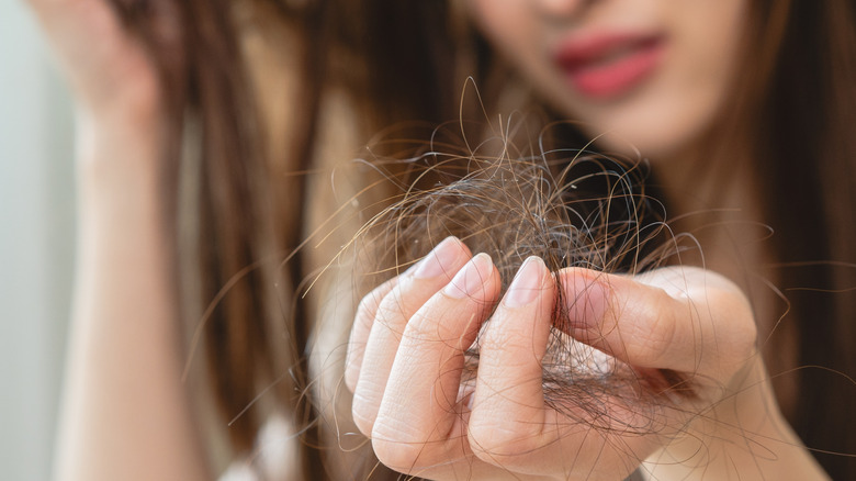 Woman holding fallen hair in hand