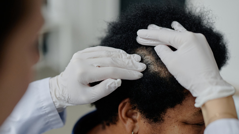 Doctor examining woman's hair and scalp