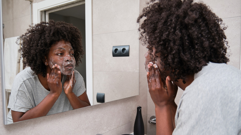 Woman washing face in mirror