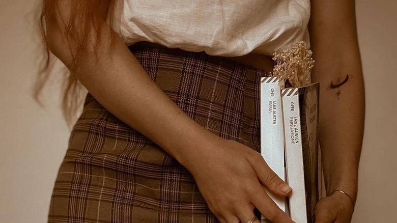 Girl in plaid skirt holding books.