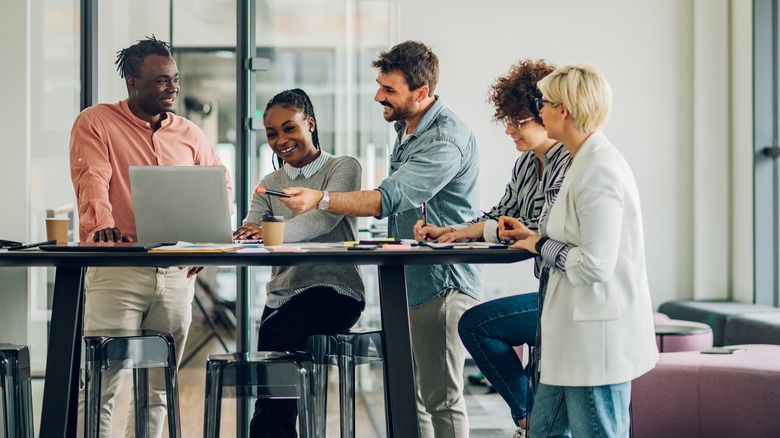 Coworkers gather around laptop