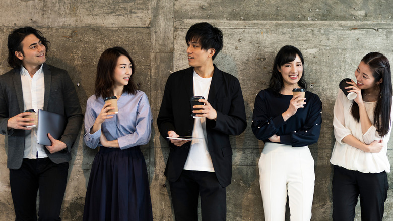 a group of young Asian professionals standing against a wall