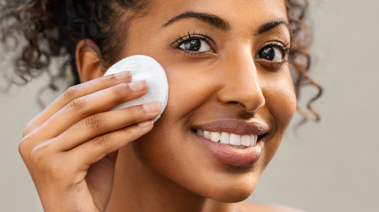 woman cleansing her face with a cotton pad