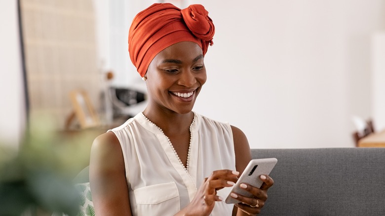 Black woman smiling at cell phone