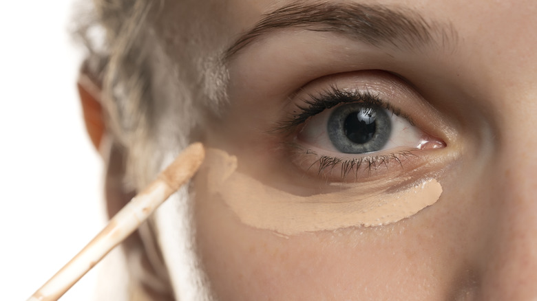 close up of woman applying concealer 