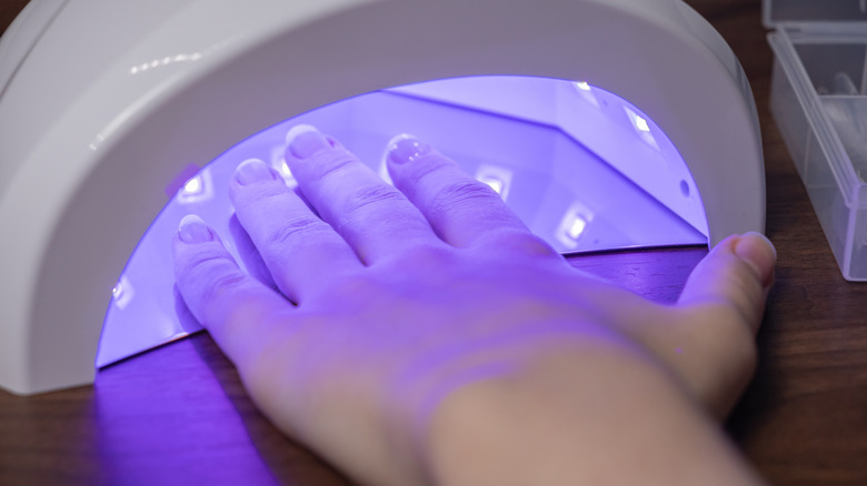 A hand under an LED curing lamp