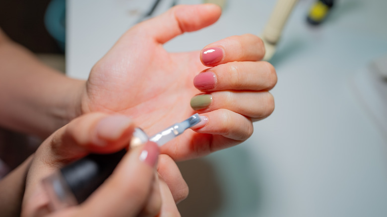 A person painting different colors of gel polish onto their nails