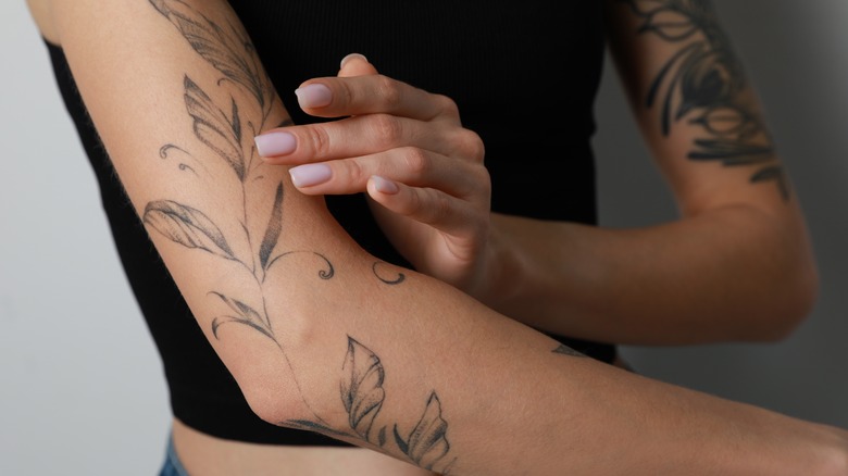 Woman examining arm tattoo