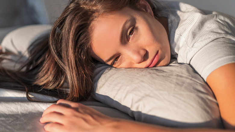 young woman laying on bed, depressed