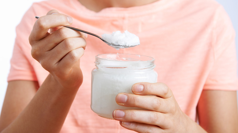 Person holding coconut oil in jar
