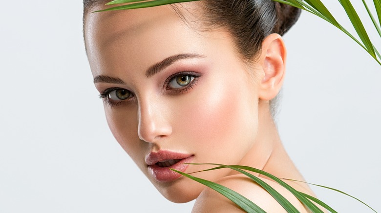 woman with makeup posing with palm leaves 