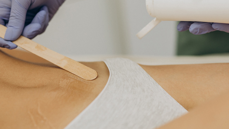 tech applying wax on bikini line