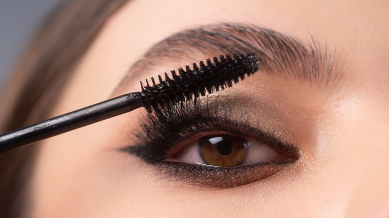 Model applying mascara to cat eye makeup
