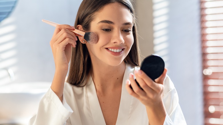 Woman applying powder to face 