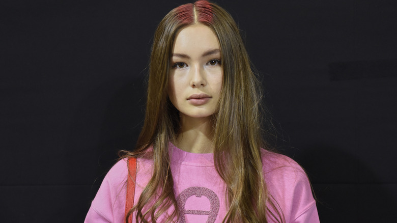 Model posing with a middle part and subtle curls