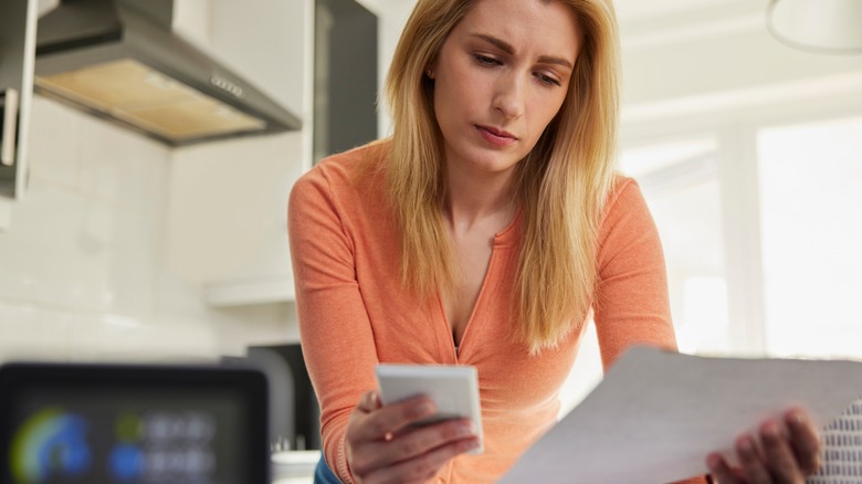 Woman dials phone while holding bill