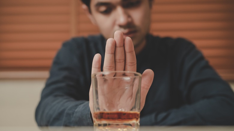 man pushing away alcohol