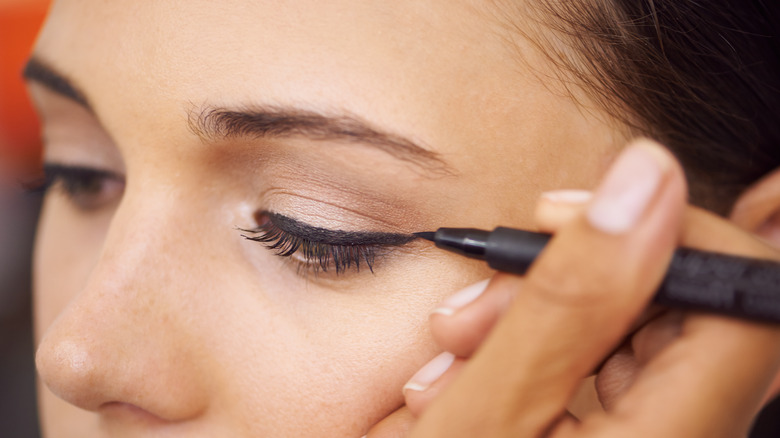 applying black eyeliner