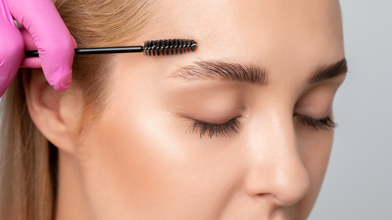 woman with thick brows brushing with spoolie