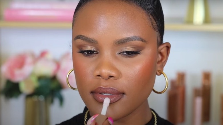 woman applying clear lip gloss