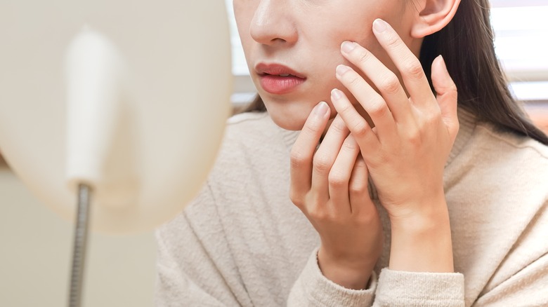 Woman checking acne in mirror