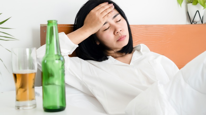 hungover woman in bed with beer
