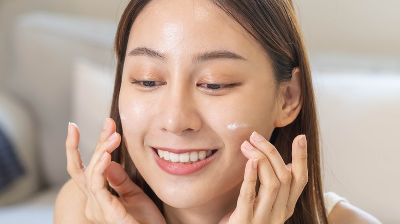 A woman putting on sunscreen